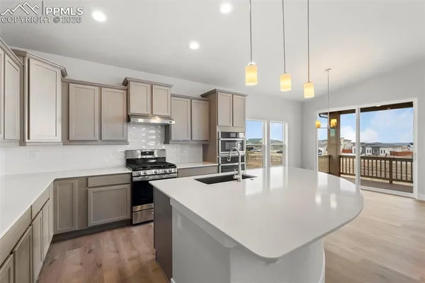 a kitchen with stainless steel appliances granite countertop a stove a refrigerator a sink a stove and white cabinets with wooden floor