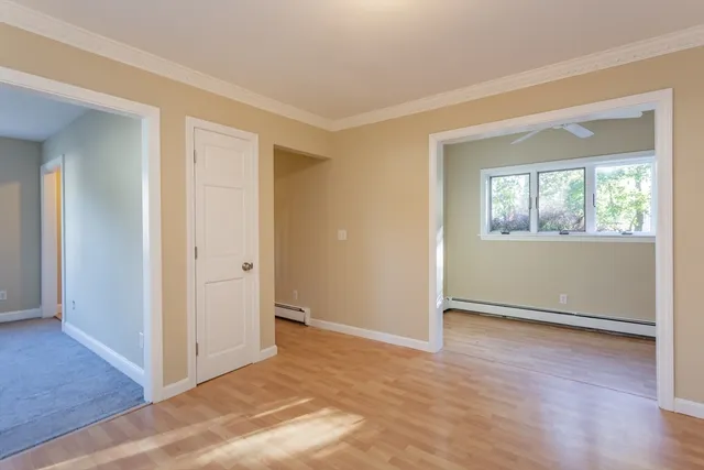 an empty room with wooden floor cabinet and windows