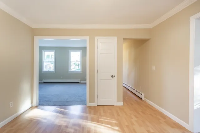 a view of a hallway with wooden floor and a bathroom