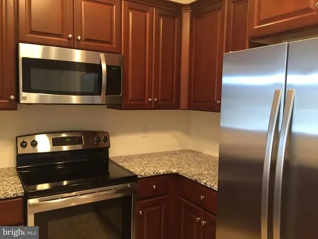 a kitchen with granite countertop stainless steel appliances and wooden cabinets