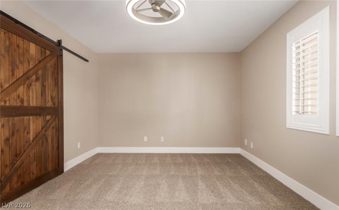 264 Pointe Ranier Avenue Henderson, NV 89012 - Photo 32 of 43 A well-lit room offers a warm ambiance with plush carpeting and a striking barn door.