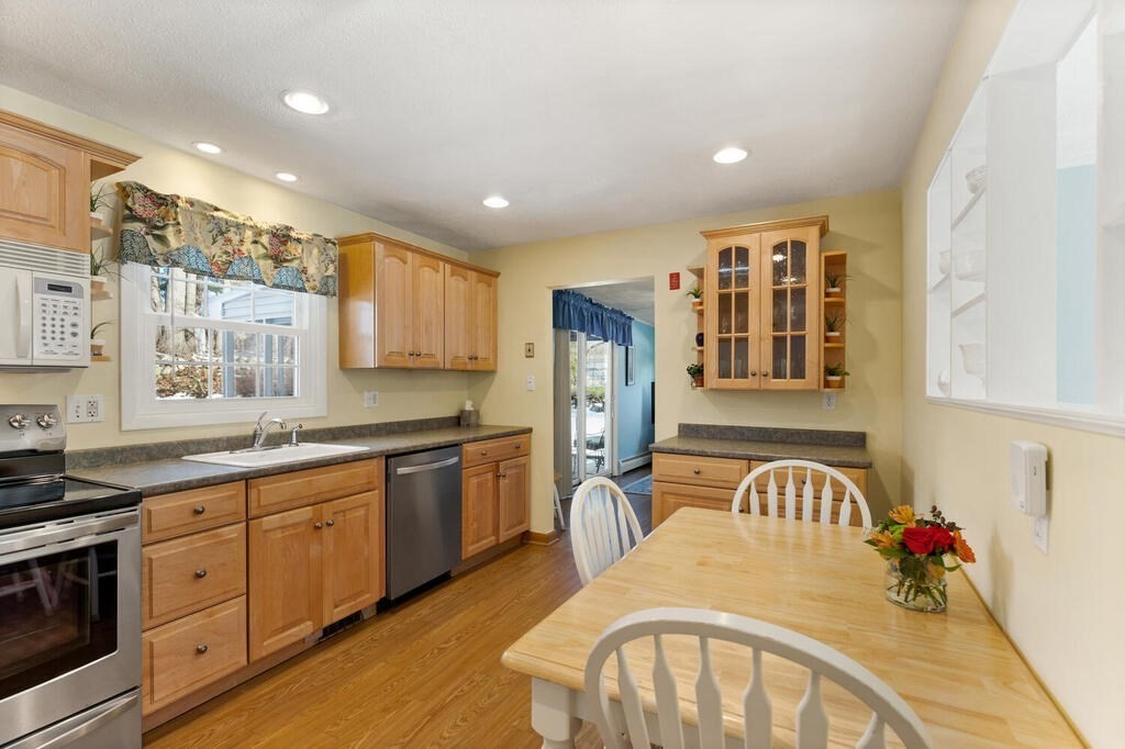 23 Walker Road Beverly, MA 01915 - Photo 12 of 33 a kitchen with stainless steel appliances granite countertop a refrigerator a stove top oven a sink dishwasher and white cabinets with wooden floor