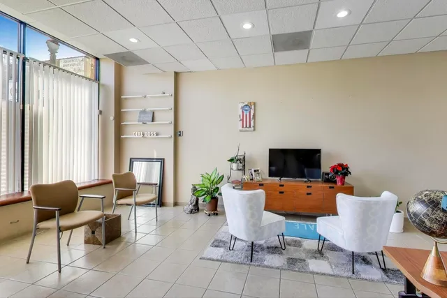 a work room with furniture a flat screen tv and a large window
