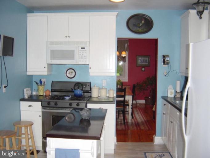 6508 Banbury Road Baltimore, MD 21239 - Photo 9 of 26 a kitchen with stainless steel appliances granite countertop a stove top oven a clock and cabinets