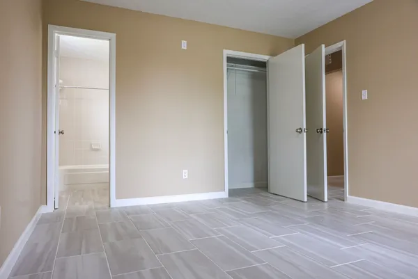 a view of an empty room with wooden floor and closet