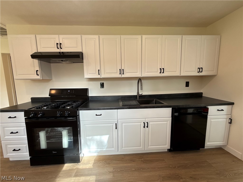 4841 Marigold Road Mentor, OH 44060 - Photo 2 of 12 Kitchen featuring white shaker-style cabinetry, dark countertops, wood-finish flooring, a black gas range with a matching range hood, and a black dishwasher