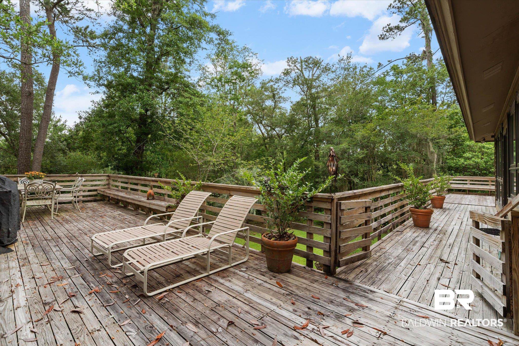 3500 Venetia Road Mobile, AL 36605 - Photo 29 of 56 Expansive wood deck with a slatted wood railing, built-in wooden bench seating, and surrounding mature trees