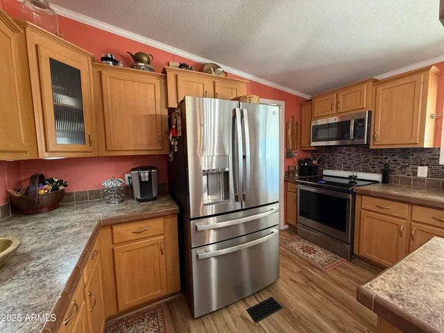 a kitchen with stainless steel appliances granite countertop a sink dishwasher a refrigerator and wooden cabinets with wooden floor