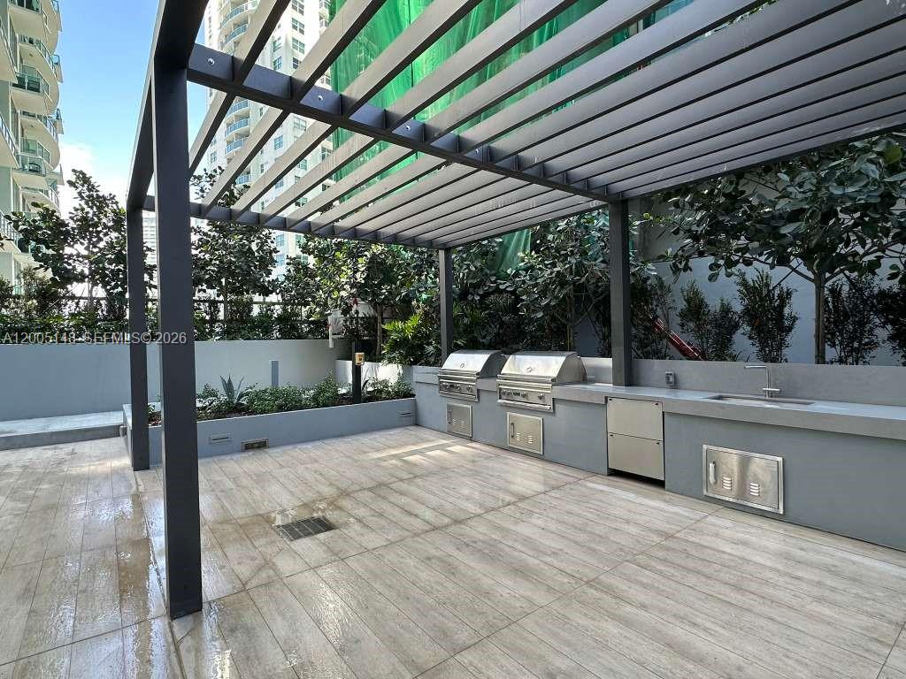 77 Southeast 5th Street, Unit 1815 Miami, FL 33131 - Photo 33 of 49 a view of a patio with table and chairs a barbeque with wooden floor and roof with a small garden