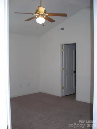 an empty room with a fan & a ceiling fan