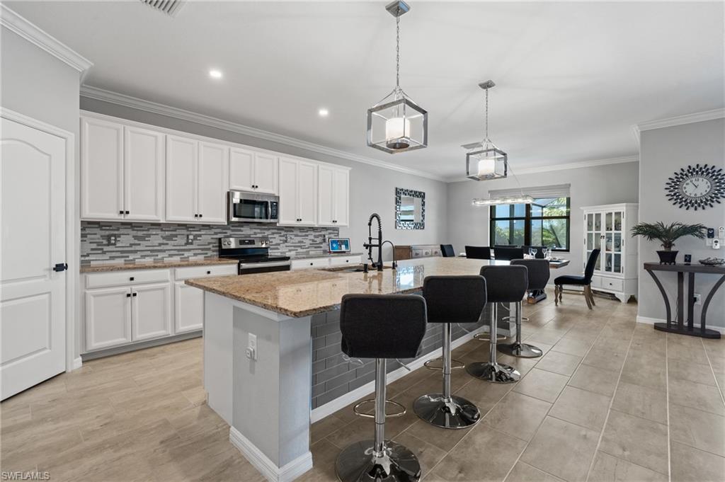 19656 The Pl Boulevard Estero, FL 33928 - Photo 14 of 42 a large kitchen with cabinets chairs and a sink