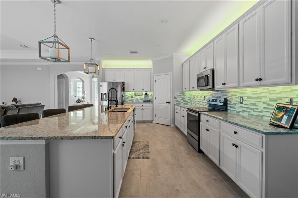 19656 The Pl Boulevard Estero, FL 33928 - Photo 16 of 42 a kitchen with stainless steel appliances granite countertop a sink a stove and a refrigerator