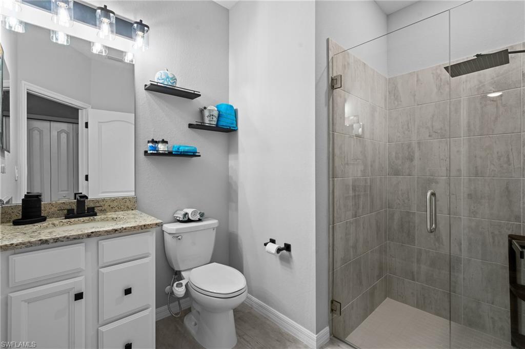 19656 The Pl Boulevard Estero, FL 33928 - Photo 25 of 42 a bathroom with a granite countertop sink a toilet and shower
