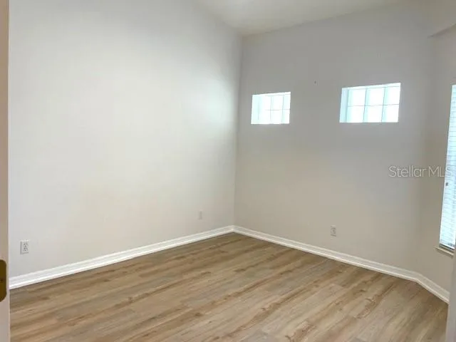 a view of an empty room with wooden floor and a window