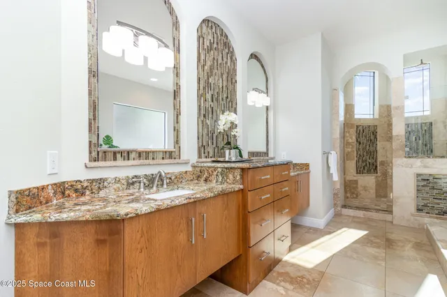 a bathroom with a granite countertop sink a large mirror and a shower