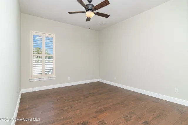 an empty room with wooden floor fan and windows