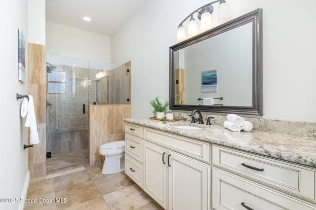a bathroom with a granite countertop sink mirror vanity and toilet