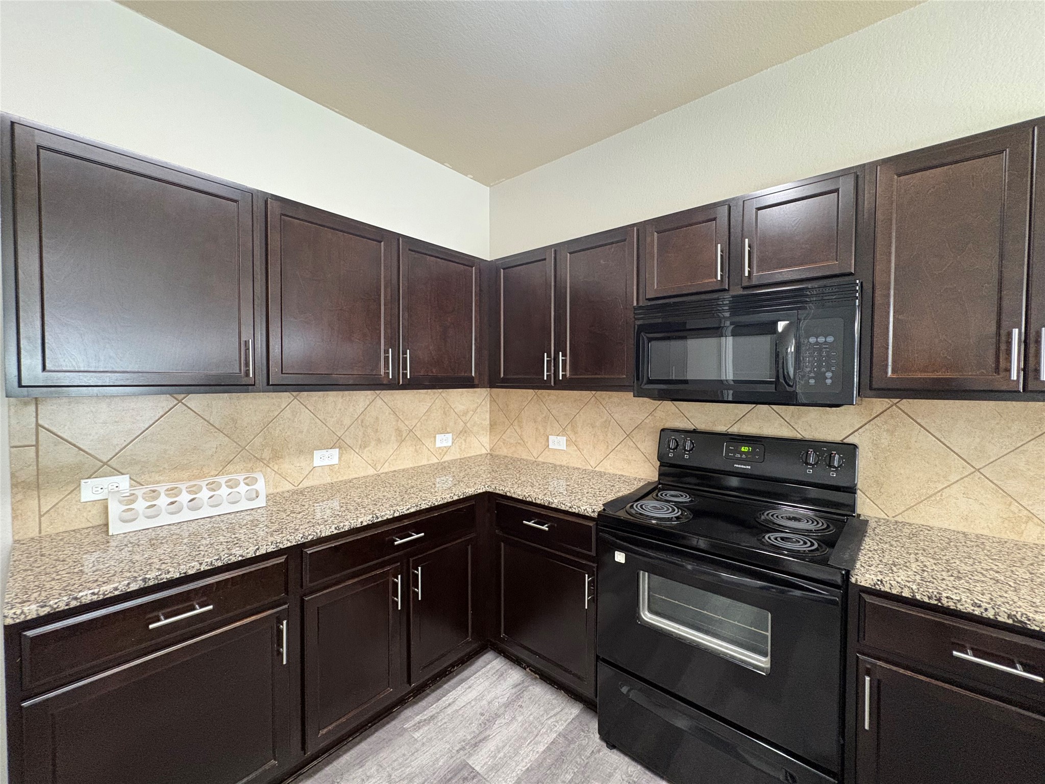 11708 Cambrian Road Manor, TX 78653 - Photo 24 of 31 Functional kitchen with dark cabinetry and granite counters provides an inviting culinary space.