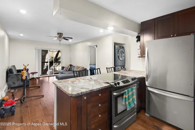 a kitchen with stainless steel appliances granite countertop a stove a refrigerator and a dining table