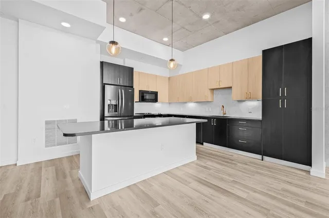 a large kitchen with stainless steel appliances granite countertop a refrigerator a sink dishwasher a stove and a refrigerator with wooden floor