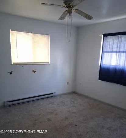 an empty room with a windows and a ceiling fan