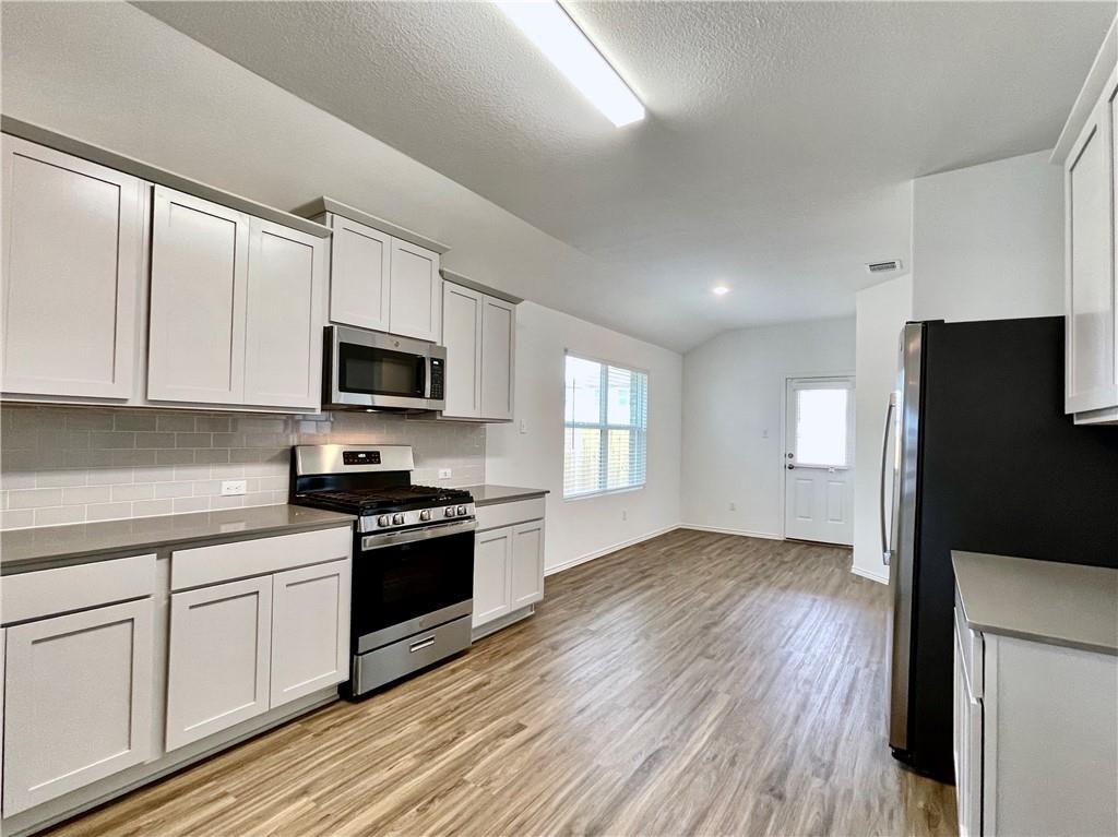 126 Canley Loop Hutto, TX 78634 - Photo 13 of 24 a kitchen with a refrigerator stove and wooden cabinets