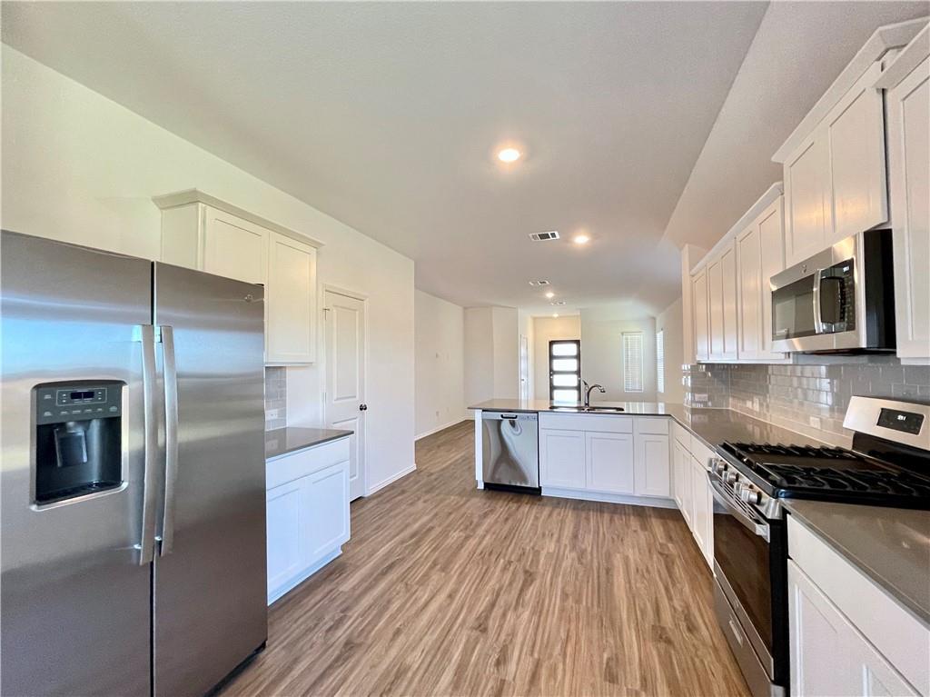 126 Canley Loop Hutto, TX 78634 - Photo 7 of 24 a large kitchen with a center island wooden floor stainless steel appliances and cabinets