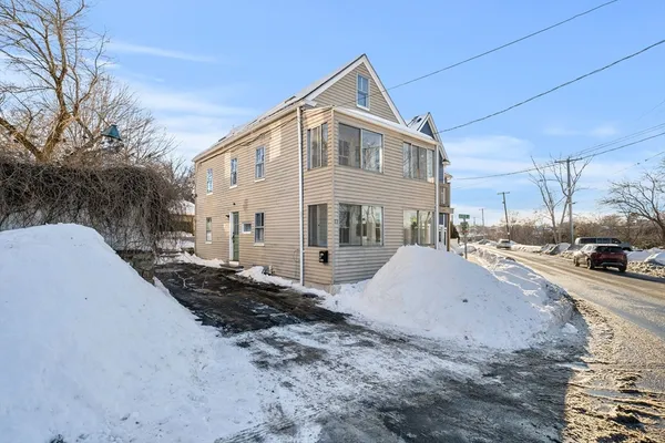 a view of a white house with a yard covered in snow