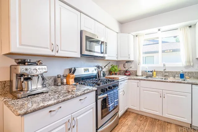 a kitchen with granite countertop white cabinets and white appliances
