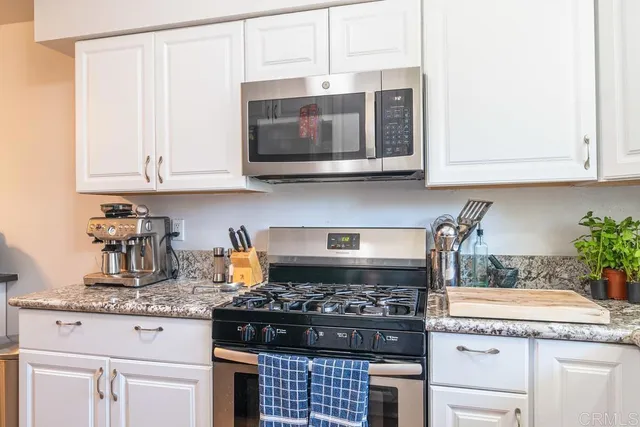 a kitchen with granite countertop a stove and a white cabinets