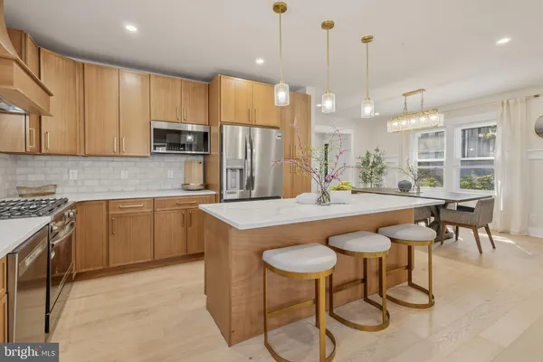 a kitchen with stainless steel appliances granite countertop a kitchen island a stove a table and chairs in it