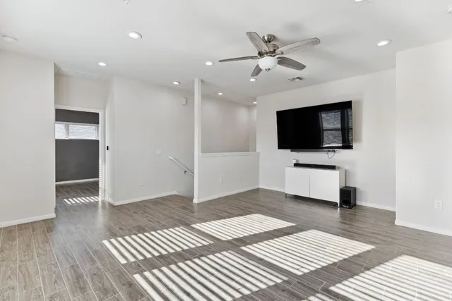 a view of a livingroom with a flat screen tv wooden floor and a ceiling fan