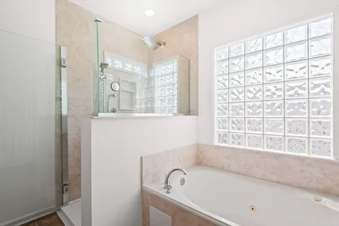 a bathroom with a bathtub a shower and a window