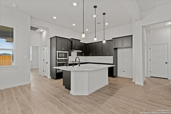 a large kitchen with stainless steel appliances a large counter top a stove a refrigerator and a sink