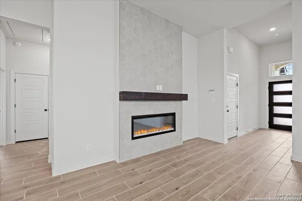 a view of an empty room with wooden floor and a fireplace