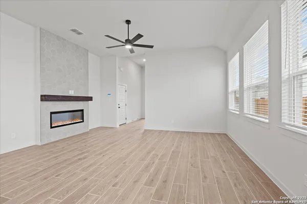 a view of empty room with wooden floor and fan