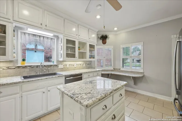 a kitchen with granite countertop a sink and dishwasher with a granite countertops next to a window