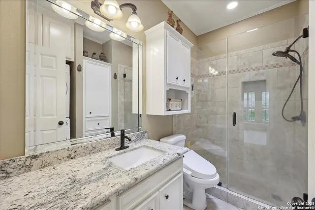 a bathroom with a granite countertop sink a toilet and shower