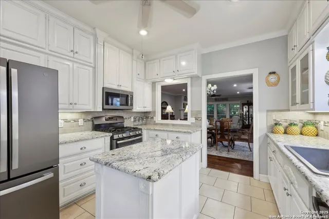 a kitchen with stainless steel appliances granite countertop a refrigerator oven stove a sink and white cabinets