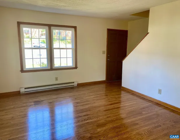 a view of an empty room with wooden floor and a window