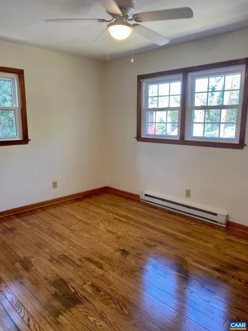 a view of an empty room with window and wooden floor