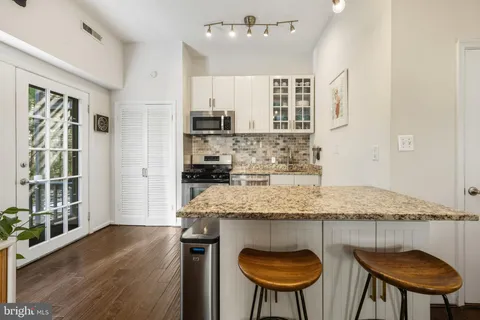 a kitchen with kitchen island granite countertop wooden floor and a refrigerator