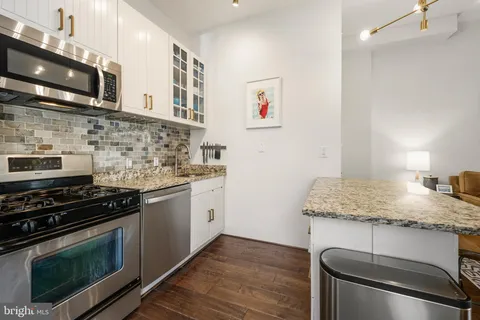 a kitchen with granite countertop a stove top oven microwave and cabinets