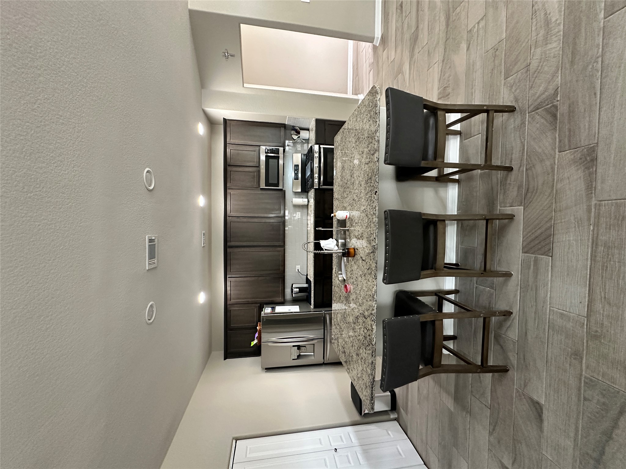 1269 Nevarez Kyle, TX 78640 - Photo 3 of 27 Kitchen with a kitchen breakfast bar, dark wood finish cabinetry, stainless steel appliances, a kitchen island with sink, and recessed lighting