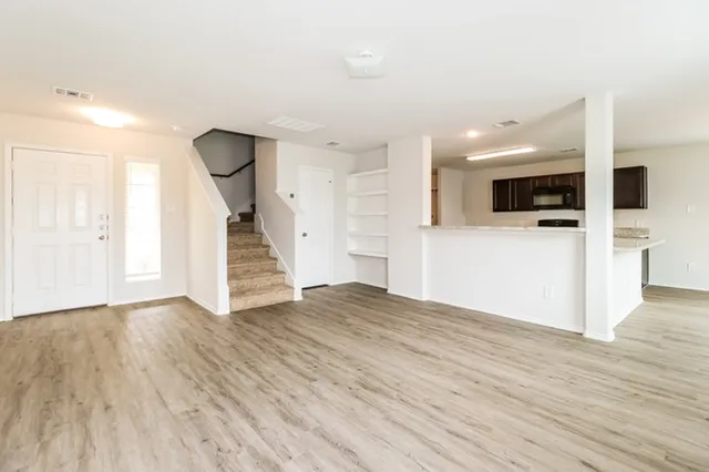a view of a livingroom with wooden floor and staircase