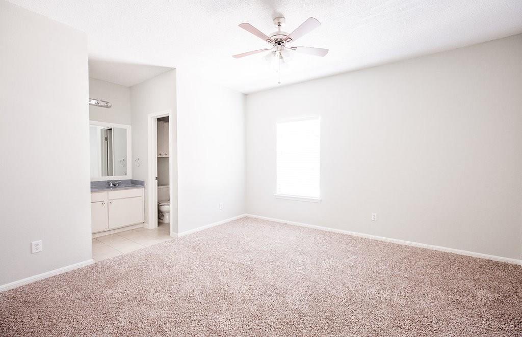 3707 Buffalo Springs Trail, Unit 301 Georgetown, TX 78628 - Photo 12 of 15 Unfurnished bedroom featuring light colored carpet, ensuite bath, and a ceiling fan