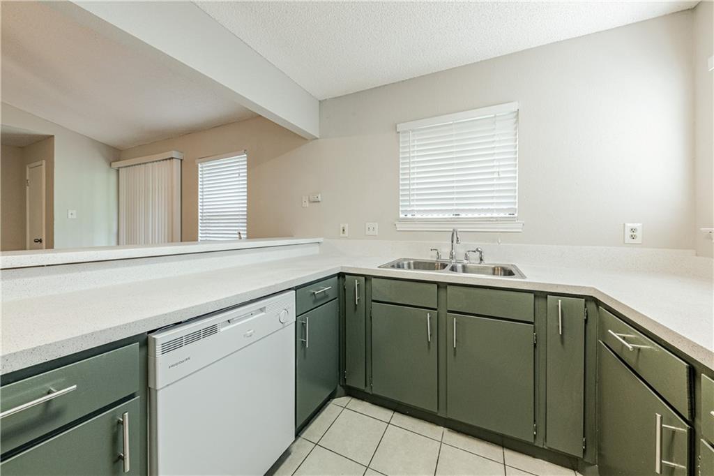3707 Buffalo Springs Trail, Unit 301 Georgetown, TX 78628 - Photo 5 of 15 Kitchen featuring green cabinetry, white dishwasher, light tile patterned flooring, a textured ceiling, and light stone counters