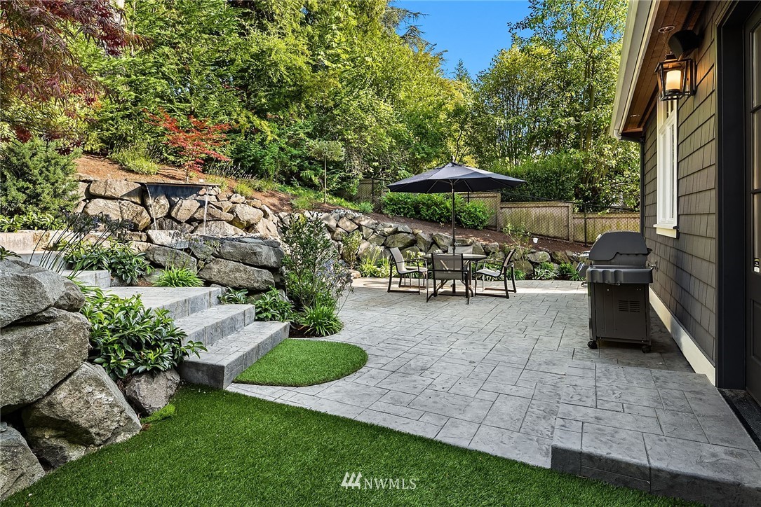 3112 Hunts Point Circle Hunts Point, WA 98004 - Photo 38 of 40 a view of a patio with table and chairs under an umbrella with a barbeque