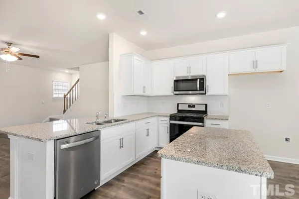 a kitchen with granite countertop white cabinets and a sink