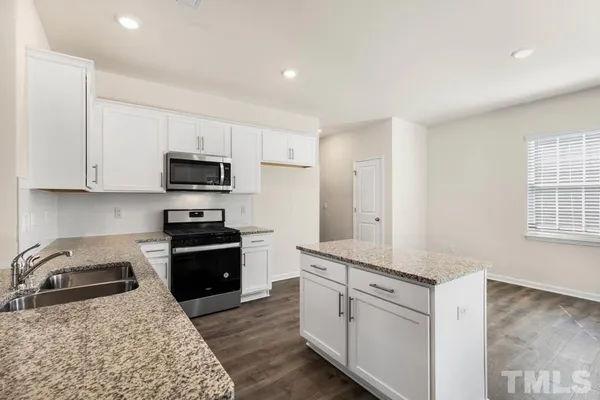 a kitchen with a sink a stove top oven a refrigerator and white cabinets